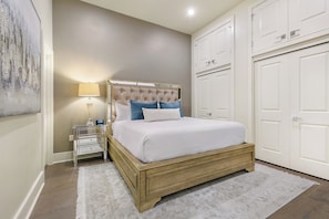 Spacious master bedroom 1 with a king bed, ensuite bath, and designer built-in closets. Includes a nightstand, lamp, hangers, luggage racks, alarm clock, white noise machine, and a 50'' Samsung Smart 4K TV with streaming and DIRECTV Entertainment.