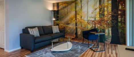 Living room with large wooded forest mural and a view of the lush green lawn. 