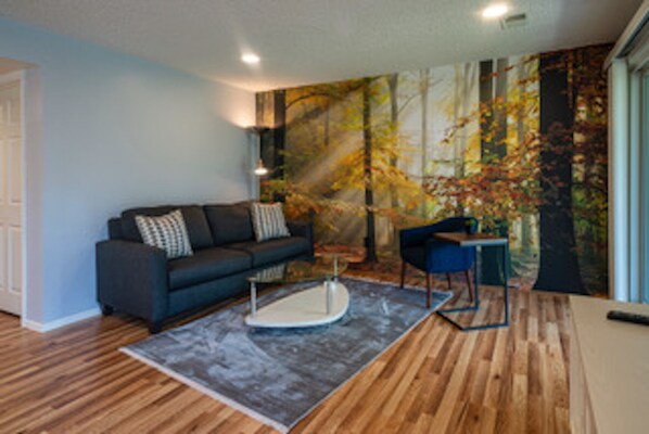 Living room with large wooded forest mural and a view of the lush green lawn. 