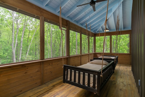 There are two swinging beds on the screened in porch.