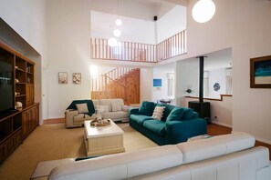 Sink into comfort in the stylish downstairs living room, where two crisp white sofas frame a bold teal centrepiece.