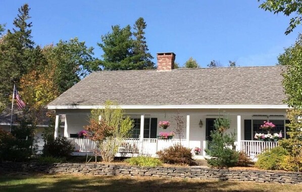 The house, shown with the front porch, sits atop a small knoll off the street.