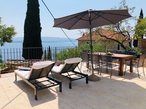 terrace, with sun chair , umbrella and outside table, and amasing view n the sea