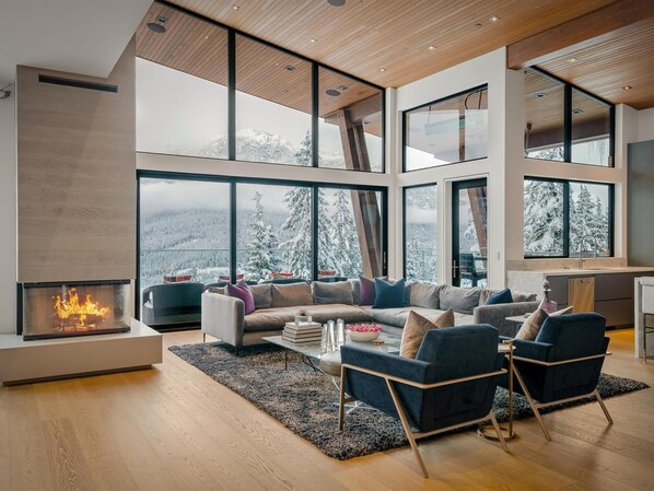 Impressive panoramic views from all rooms, including the grand great room with floor-to-ceiling windows, cosy wood-burning fireplace, large heated terrace