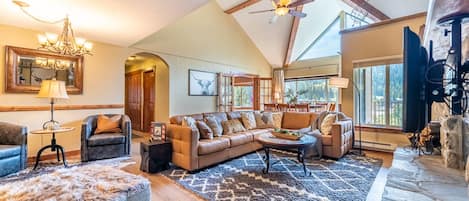 Spacious living area featuring large wood burning fireplace, ample seating and sweeping mountain views.