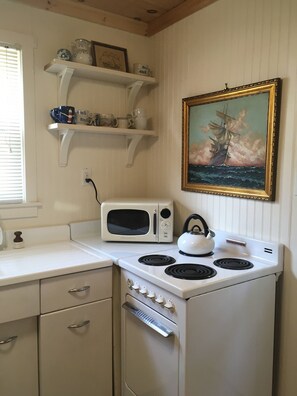 Tea Kettle, stove, vintage coastal oil paintings throughout the cottage.