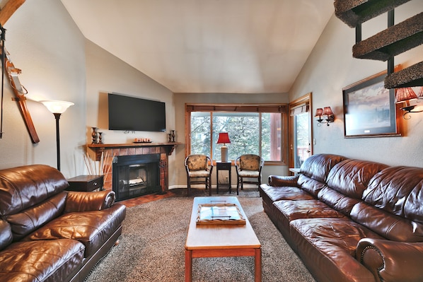 Living room features a brown leather couch and love seat, and two wooden chairs by the picture window