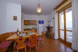 The living room with dining table, TV and entrance to the balcony