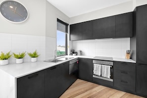 Modern kitchen with marble-look stone countertops and black accents throughout. 