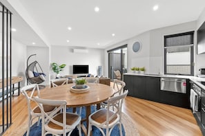 An open plan kitchen has everything you need to prepare delicious meals, or indulge in a plethora of local takeaway options, complete with a beautiful dining table.