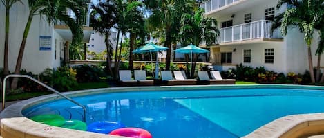 Large swimming pool with poolside loungers and umbrellas