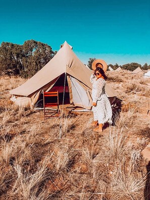 A guest tips their hat on a clear, blue sky day after bringing out a chair from their tent to enjoy the beauty.