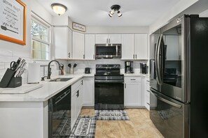 Modern kitchen equipped w/ an electric range & large capacity fridge