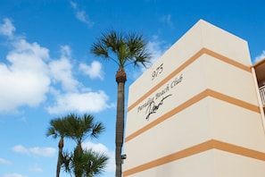 Elegant exterior of Paradise Beach Club, surrounded by palm trees and blue skies.