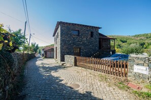 Fachada da casa, lugar para dois carros dentro do portão de madeira.
