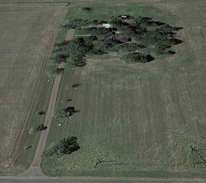 Aerial view, The Farm is nestled in the trees, surrounded by hay fields.