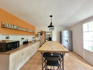 Coin repas, table en bois massif, réfrigérateur grande capacité.