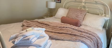 Comfortable Q size bed, soft pink throw & hotel quality towels