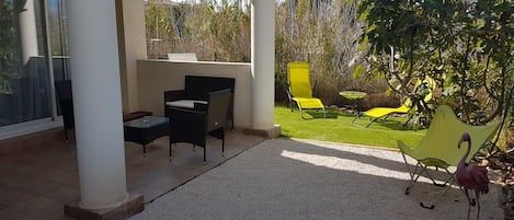 Extérieur avec terrasse abritée et jardin arboré. 