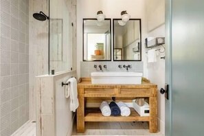 Bathroom with double vanity, large walk in shower, and toilet. 