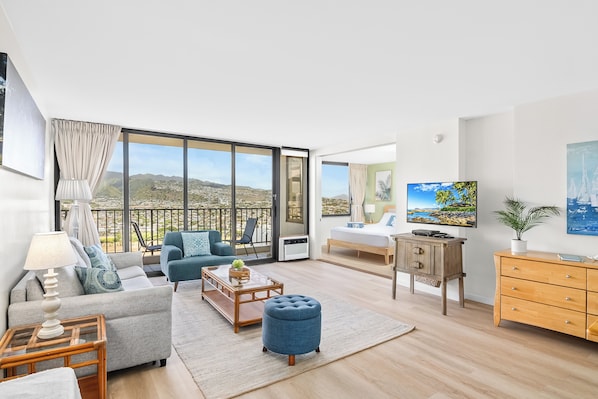 Living room with beautiful mountain and city views, pull out sleeper sofa, window AC, flat screen TV.
