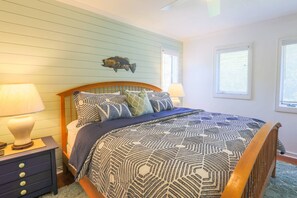 The bedroom features a king bed, a shiplap wall and nightstands with reading lamps.