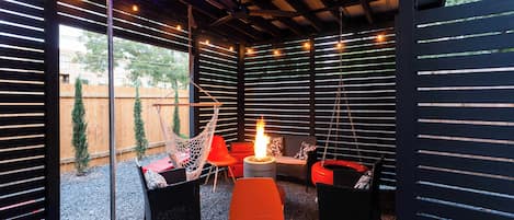 Covered Patio With Fire Pit And Hanging Chairs For Relaxation