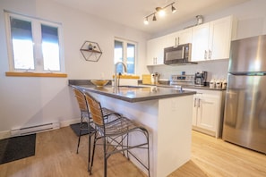 Modern Kitchen with Stainless Steel Appliances, and Two Bar Stools