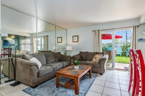 Living room with sliding glass doors out to the patio, grass, and 10 steps to the beach!