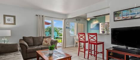 Comfortable living room with east facing patio. The beach is out the sliding door, to the right, up the common walkway to the gated entrance to the sand.