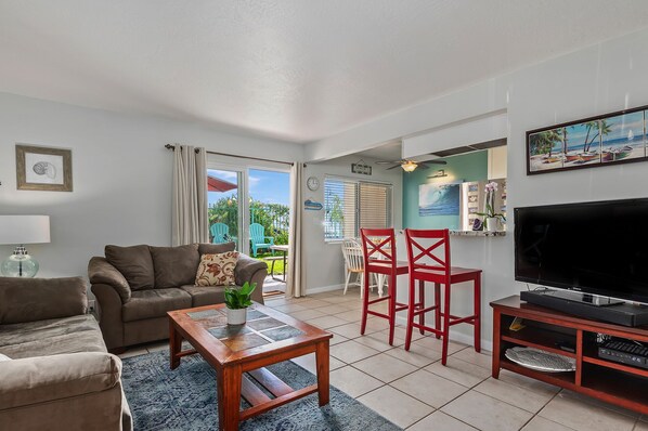 Comfortable living room with east facing patio. The beach is out the sliding door, to the right, up the common walkway to the gated entrance to the sand.