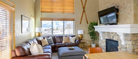 Experience the cozy living room, outfitted with plush seating, an expansive smart TV, and patio doors that frame the breathtaking mountain vistas.