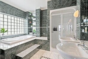 The magnificent jade green bathroom has a resort-style elegance including a large spa bath