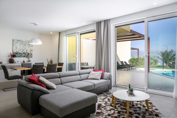 Living room with grey comfortable sofa and Smart TV in a luxury beachfront villa for family vacation in Ciovo

