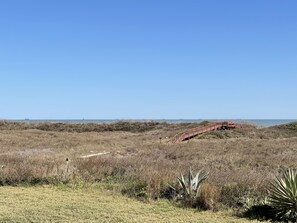 View of the boardwalk from patio. Peaks of the the water behind the dunes.