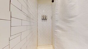 The bathroom has a beautiful, white tile enclosed shower