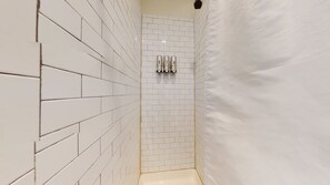 The bathroom has a beautiful, white tile enclosed shower