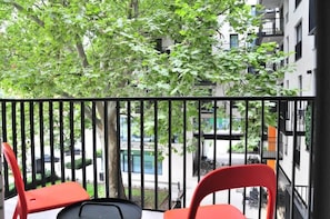A small balcony with red and black chairs, offering a relaxing outdoor space surrounded by greenery.