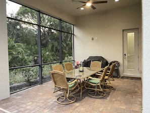 Outdoor screened dining and grill area with a pool view. 