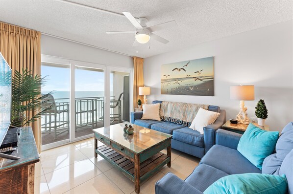 Imagine sinking into the plush blue sofa, feeling the ocean breeze drift in as the waves crash outside