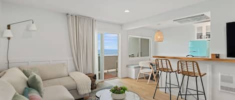 Living room with sectional sofa, breakfast bar, flat screen TV and ocean views.