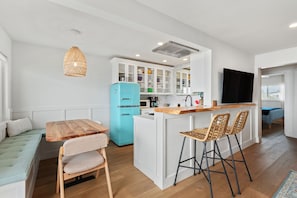 View of the kitchen dining table, bar stools, and kitchen.