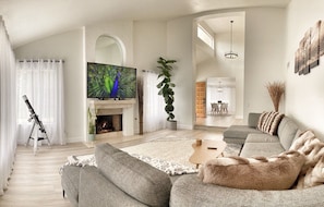 Fireplace and tall windows overlooking expansive side yard.