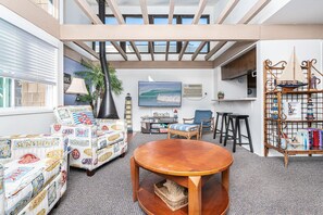 Stairs lead you to the main upper level, with sofa, side seating, cable TV, and kitchen beyond.
                