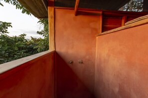 The minimalist, red clay shower is open to the surrounding jungle