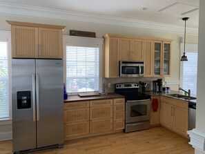 Kitchen fully stocked with plates, drinkware, utensils and cookware. 