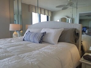 Master bedroom with comfy bed and oceanfront view with sliding glass doors.