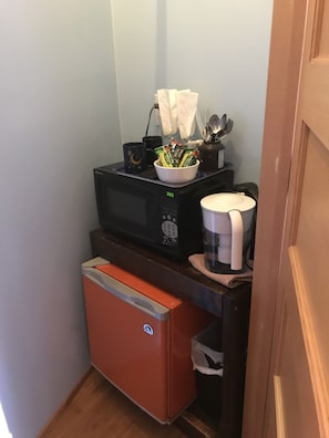 Closet with a mini fridge and a small microwave. 