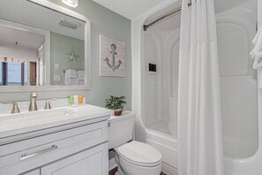 A full bathroom with tub shower, toilet, and sink.