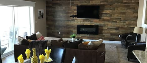 Large open concept living/dining room with wall mounted fireplace and big screen